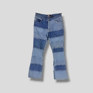 May include: Blue denim jeans with a patchwork design. The jeans are flared at the bottom and have a light blue, medium blue, and dark blue colour scheme.