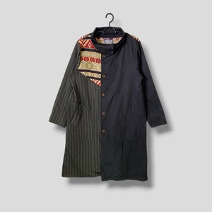 Puede incluir: Una camisa larga de rayas negras y verdes con un panel de tela estampada en la parte delantera. La camisa tiene un frente abotonado y mangas largas.