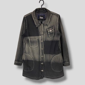 Puede incluir: Una chaqueta vaquera de manga larga con un diseño de patchwork en tonos de negro y gris. La chaqueta tiene un cierre de botones en la parte delantera, dos bolsillos en el pecho y dos grandes bolsillos de parche en la parte inferior.