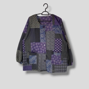 Puede incluir: Una chaqueta de patchwork con una variedad de patrones morados, azules y verdes. La chaqueta tiene un cierre de botones en la parte delantera y mangas largas.