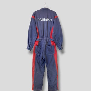 May include: A blue and red work jumpsuit with the word "DAIHATSU" printed on the back.