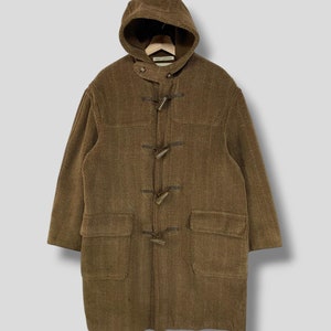 May include: A brown herringbone-patterned duffel coat with a hood and toggle closures. The coat has two large front pockets and a relaxed fit. The coat is made of a thick, warm material, perfect for cold weather.