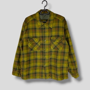 May include: A long-sleeved plaid shirt in a yellow and brown colour scheme. The shirt has a button-down collar and two chest pockets.