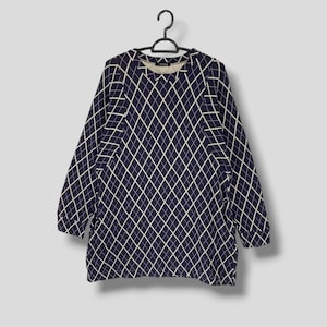 May include: A navy blue long-sleeved top with a white diamond pattern. The top is hanging on a black hanger. The garment has a crew neck and a relaxed fit, suitable for casual wear.