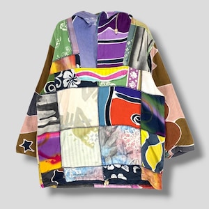 Può includere: Una giacca patchwork con una varietà di quadrati di tessuto colorati. La giacca ha un cappuccio e maniche lunghe. La tavolozza dei colori comprende sfumature di verde, viola, arancione e marrone. La giacca ha un design artistico unico.