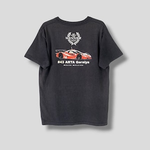 Puede incluir: Camiseta negra con un gráfico de coche de carreras rojo y blanco en la espalda. El coche está etiquetado como "#43 ARTA Garaiya" y tiene los nombres "Mario  Roble" y "Shinji  Takagi" debajo. La camiseta también tiene un pequeño círculo blanco con el texto "SUPER GT WINNER 2013" y una corona de laurel.