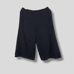 Könnte beinhalten: Schwarze Culottes mit weitem Bein. Die Shorts haben eine hohe Taille und sind aus einem strukturierten Stoff gefertigt. Das Kleidungsstück hat einen klassischen, minimalistischen Stil, der für verschiedene Outfits geeignet ist.