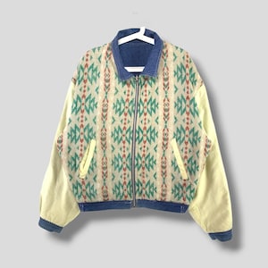 May include: A reversible jacket with a geometric pattern on one side and denim on the other. The jacket has a zipper closure and two pockets.