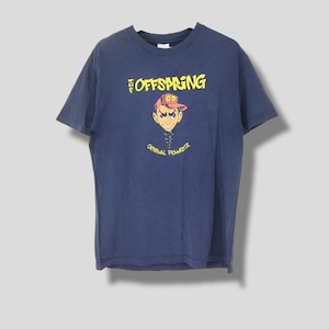Puede incluir: Una camiseta azul marino con un gráfico de un personaje de dibujos animados que lleva un sombrero rojo con el texto "O.P." en él. El texto "The Offspring" y "Original Prankster" está impreso en amarillo en la camiseta.