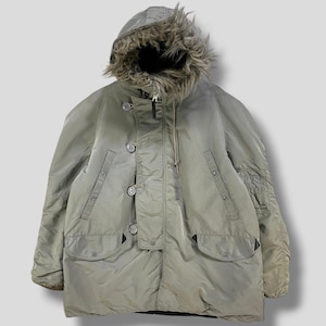 Könnte beinhalten: Salbeigrüner Winterparka mit fellgefütterter Kapuze. Die Jacke hat einen Reißverschluss, eine Knopfleiste, mehrere Taschen und eine Utility-Tasche am linken Ärmel. Der Parka ist für kaltes Wetter konzipiert.