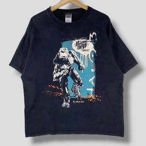 May include: A black t-shirt with a graphic print of a video game character, a Mountain Dew logo, and the text "Xbox 360".