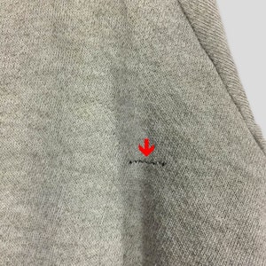 K&ouml;nnte beinhalten: Nahaufnahme eines hellgrauen Stoffes mit einem kleinen Riss. Der Stoff hat ein strukturiertes Aussehen und eine sichtbare Naht. Der Riss ist eine horizontale Linie aus gebrochenen F&auml;den.