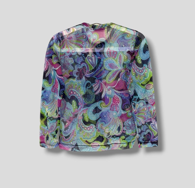 Puede incluir: Una camiseta de manga larga con cuello redondo y un vibrante estampado de cachemir. El dise&ntilde;o presenta motivos florales arremolinados en tonos azules, verdes, morados y rosas sobre un fondo oscuro. La camiseta est&aacute; hecha de una tela transparente y ligera.