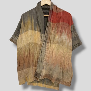 May include: A short-sleeved open-front jacket featuring a textured, woven fabric with a multi-colored abstract pattern in shades of brown, tan, gray, and rust red. The garment has a wide collar and a loose, relaxed fit with visible frayed edges.