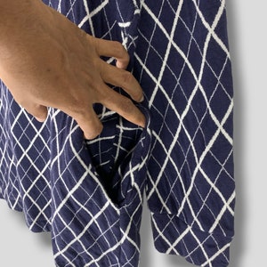 May include: Navy blue long-sleeve shirt with a white diamond pattern. The shirt has a pocket on the side. The fabric appears to be a soft knit material.
