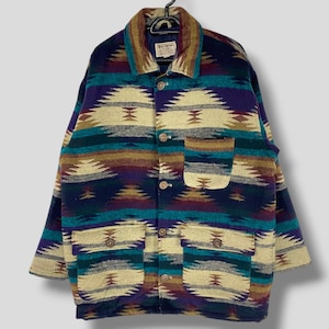 Könnte beinhalten: Eine mehrfarbige gewebte Jacke mit einem südwestlichen Muster. Die Jacke hat einen Knopfschließe, lange Ärmel und zwei große Taschen. Der Stoff ist eine Mischung aus Wolle und Acryl.