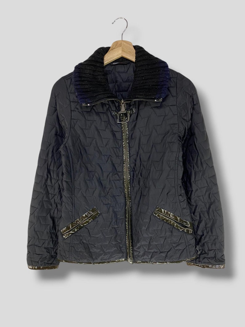 May include: A black quilted jacket with a zipper closure and a black knit collar. The jacket has a diamond pattern and a shiny black trim.