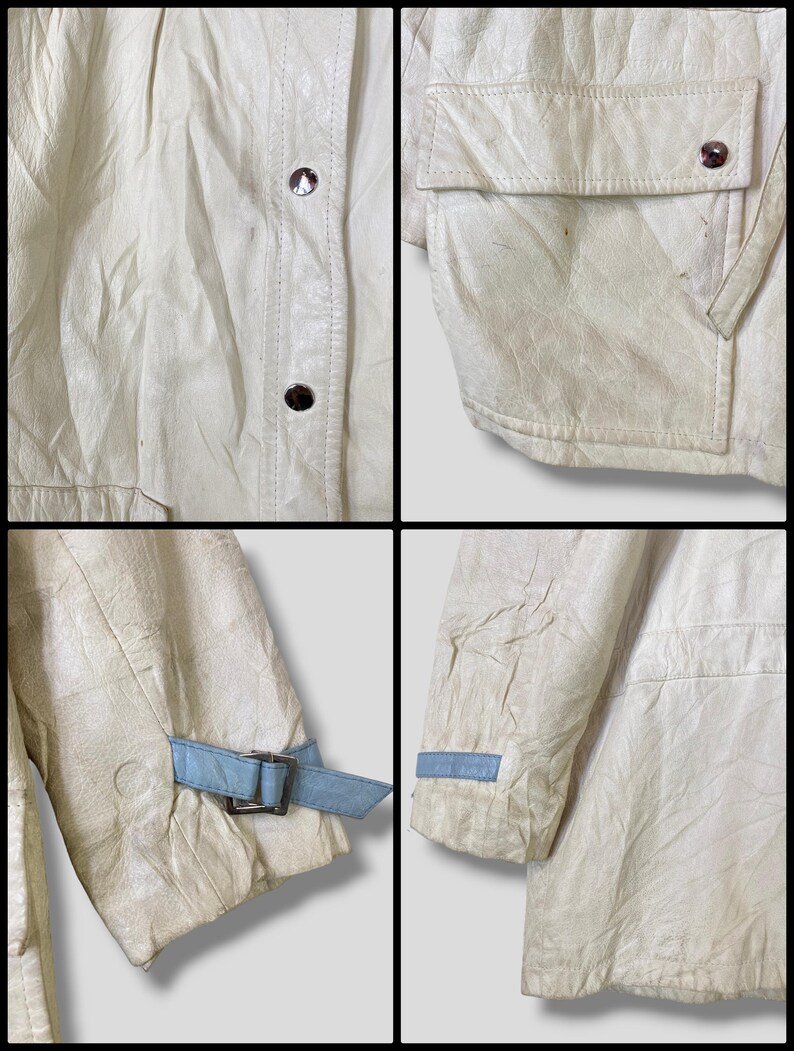 Puede incluir: Una chaqueta de cuero blanca con un detalle de correa azul en las mangas. La chaqueta tiene una cremallera y un bolsillo de solapa en la parte delantera.