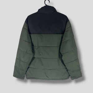 May include: A two-tone puffer jacket in black and olive green, hanging on a black hanger. The jacket has a high collar and horizontal quilted stitching. The back view shows the jacket's design and construction.
