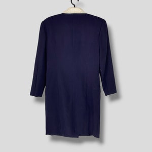Puede incluir: Una chaqueta azul marino con cuello blanco y ribete de cuentas. La chaqueta tiene mangas largas y un cierre de bot&oacute;n &uacute;nico.