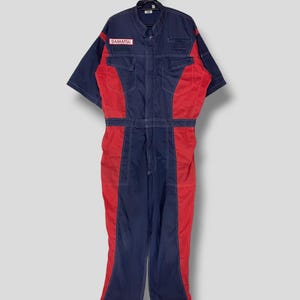 May include: A blue and red work jumpsuit with short sleeves and the word "DAIHATSU" on the left chest.