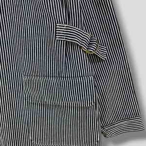 May include: A blue and white striped workwear jacket with a large pocket on the front and a metal ring on the sleeve.