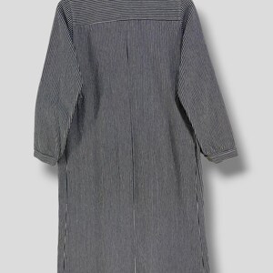 May include: A long-sleeved, striped shirt dress with a button-up front and a collar. The shirt dress is black and white with thin vertical stripes.