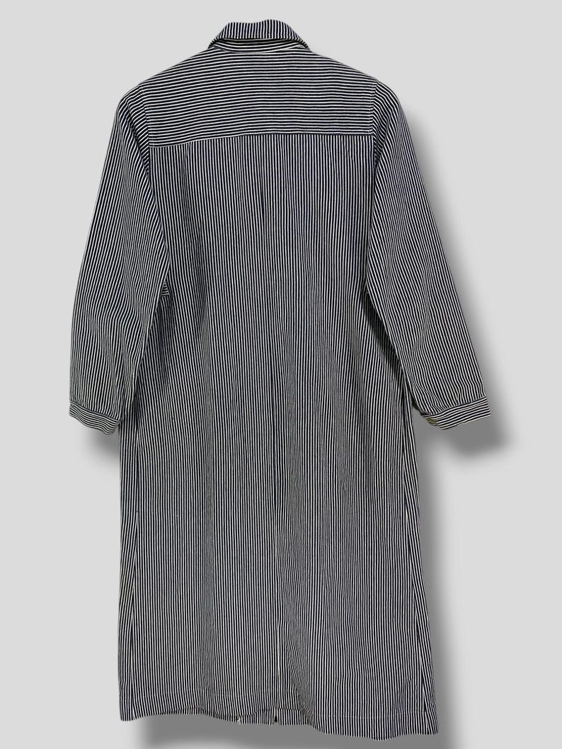 May include: A long-sleeved, striped shirt dress with a button-up front and a collar. The shirt dress is black and white with thin vertical stripes.