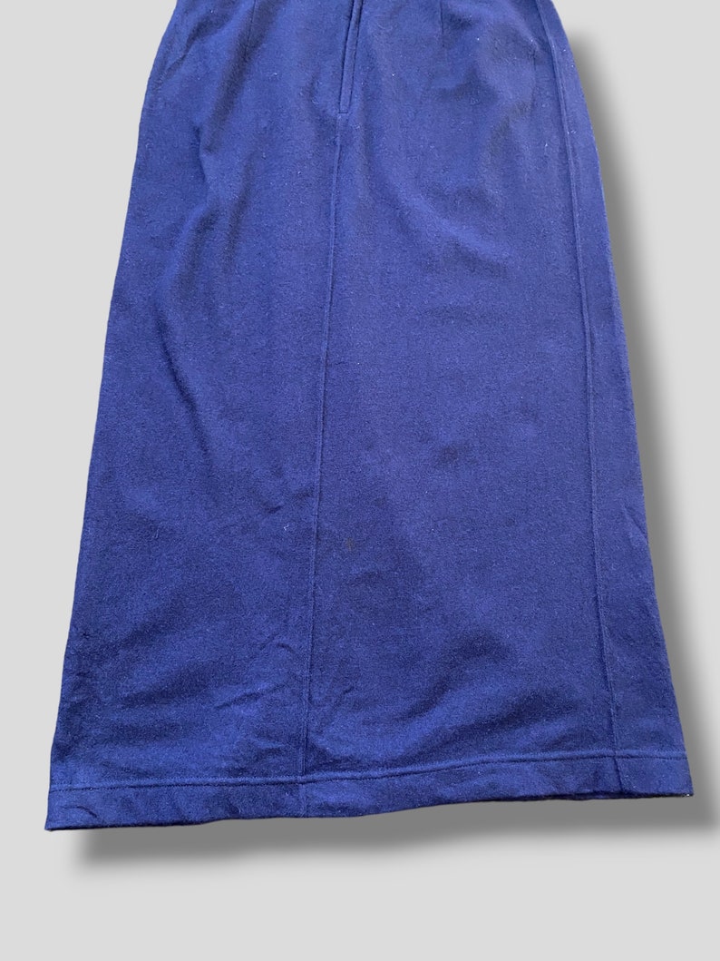 Puede incluir: Primer plano de una falda azul marino. La falda es de color liso y parece estar hecha de una tela suave. La falda tiene una costura en la parte delantera y un dobladillo en la parte inferior.