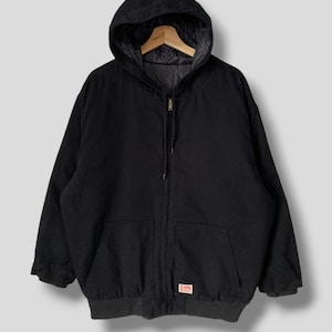 以下が含まれることがあります： ジッパー留めと右下に小さな赤いラベルが付いた黒いフード付きジャケットです。