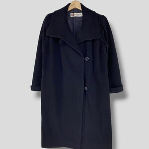 May include: A long black coat with a large collar and a single button closure. The coat has a simple design and is made of a smooth fabric.