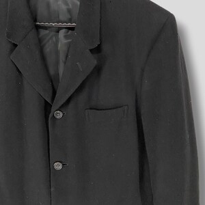 May include: A black blazer with a single-breasted closure and three buttons. The blazer has a pocket on the left chest and two pockets on the bottom.
