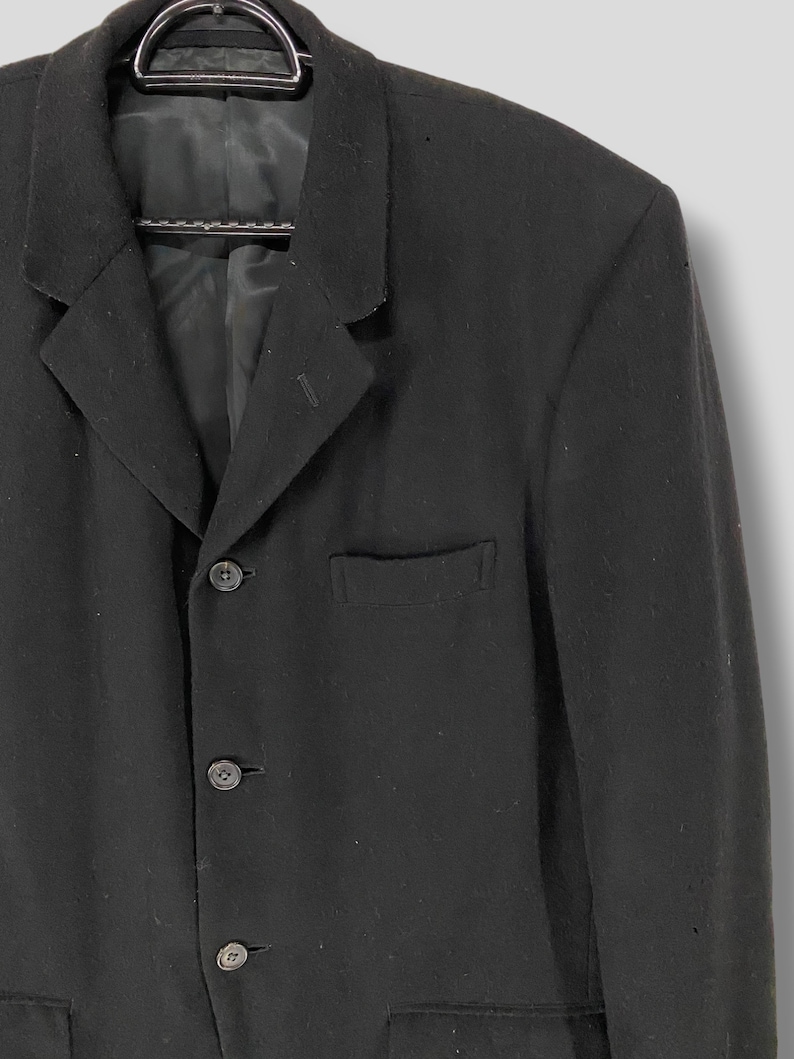 May include: A black blazer with a single-breasted closure and three buttons. The blazer has a pocket on the left chest and two pockets on the bottom.