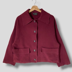 Puede incluir: Una chaqueta de botones color burdeos con dos bolsillos grandes y cuello.