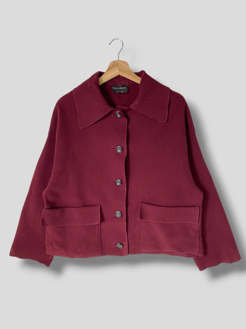 Puede incluir: Una chaqueta de botones color burdeos con dos bolsillos grandes y cuello.