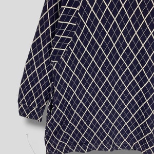 May include: Navy blue long-sleeve shirt with a white diamond pattern. The pattern covers the entire shirt, including the sleeves. The shirt is made of a soft, comfortable material.