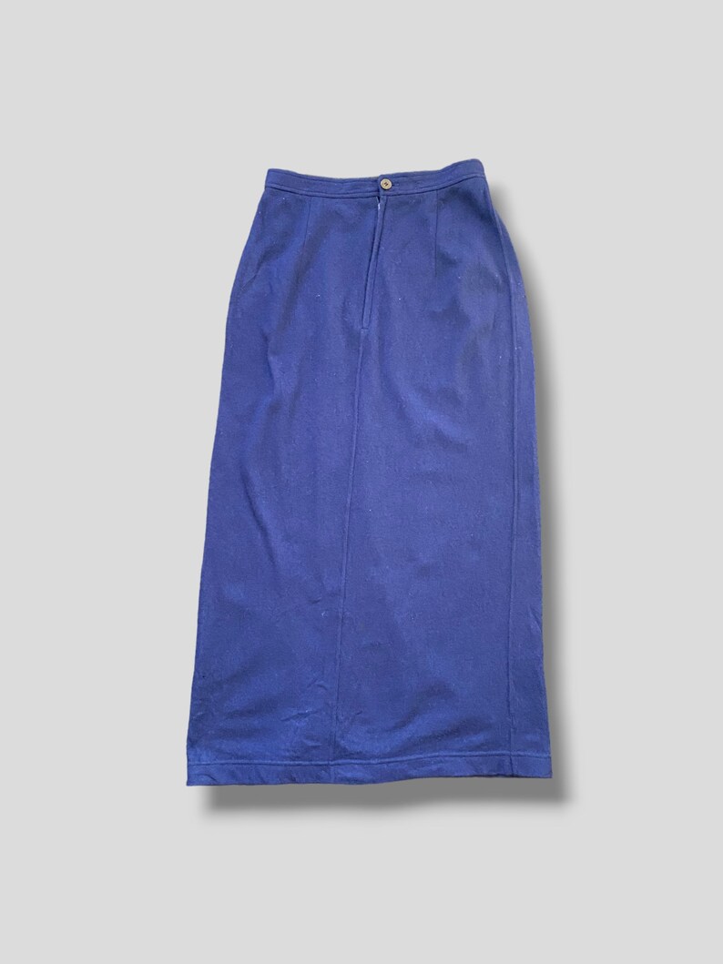 Puede incluir: Una falda larga azul marino con cintura alta y silueta recta. La falda tiene cierre de cremallera y bot&oacute;n en la cintura. La tela parece ser un material de peso medio, adecuado para diversas ocasiones.