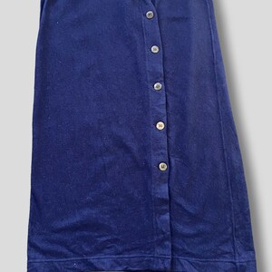 Puede incluir: Una falda azul marino con botones en la parte delantera. La falda est&aacute; hecha de una tela suave y tiene siete botones en el lateral. La falda es de color liso y tiene un dise&ntilde;o sencillo y cl&aacute;sico.