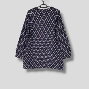 May include: Navy blue long-sleeve sweater with a white diamond pattern. The sweater is hanging on a black hanger against a light gray background. The sweater has a crew neck and long sleeves.