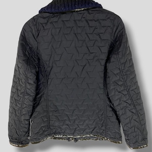 May include: Black quilted jacket with a navy blue and gray knit collar. The jacket has a diamond pattern and a zipper closure.