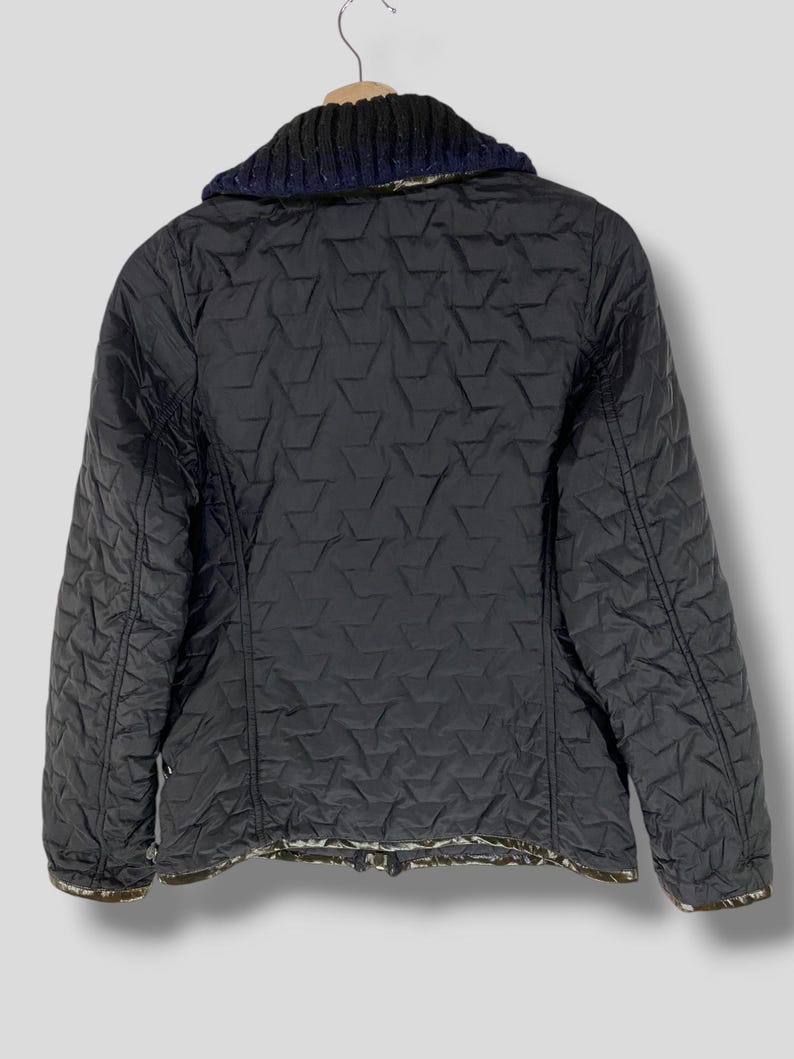 May include: Black quilted jacket with a navy blue and gray knit collar. The jacket has a diamond pattern and a zipper closure.