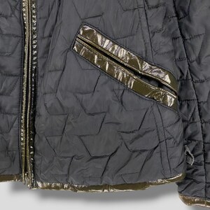 May include: A black quilted jacket with a zipper closure and a brown leather trim. The jacket has a pocket on the left side and a quilted pattern.