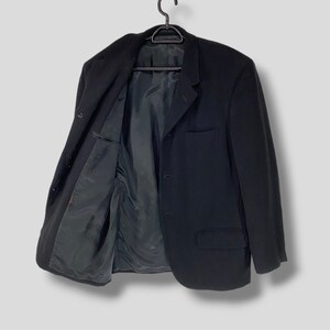 May include: A black blazer with a single button closure and two pockets. The blazer is hanging on a black hanger.