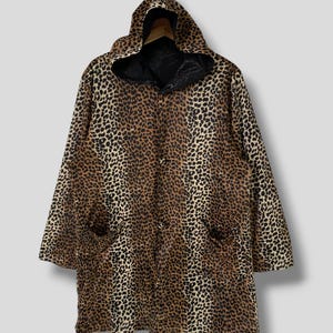 May include: A long-sleeved hooded jacket with a leopard print pattern. The jacket has a button closure and two pockets.
