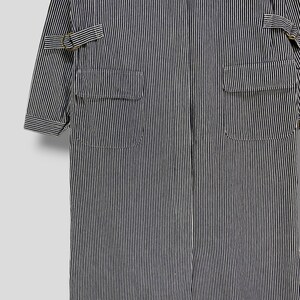 May include: A long, black and white striped workwear jacket with two large pockets and a zipper closure.