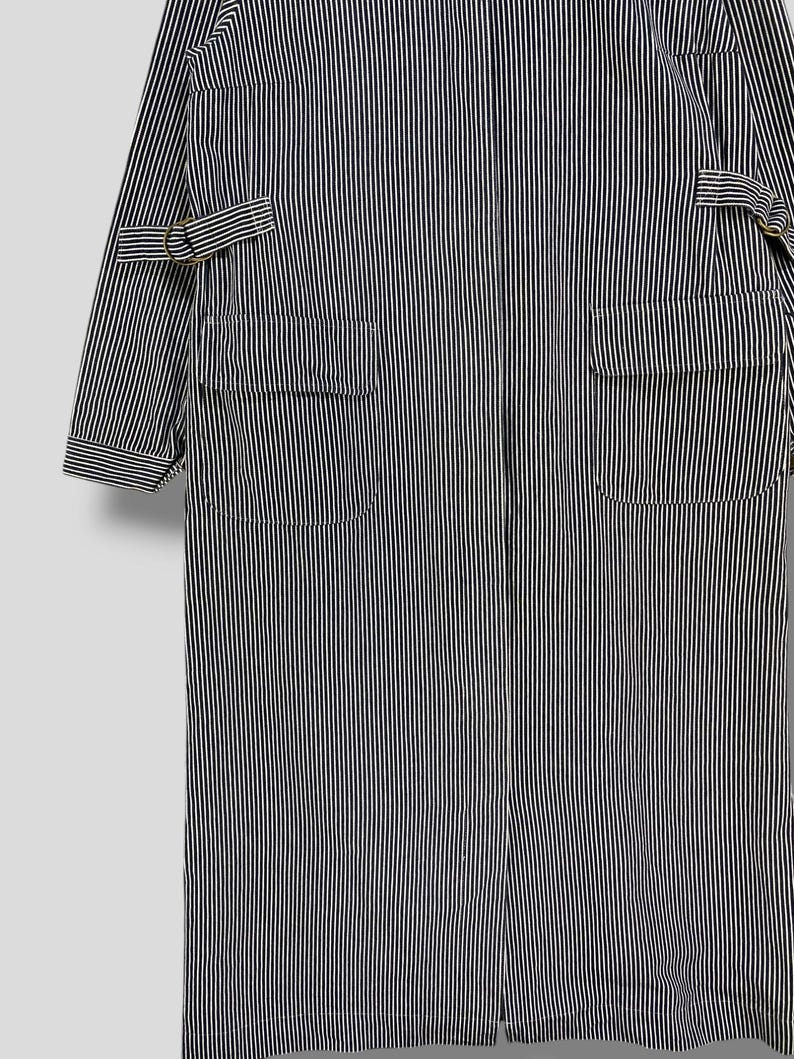 May include: A long, black and white striped workwear jacket with two large pockets and a zipper closure.