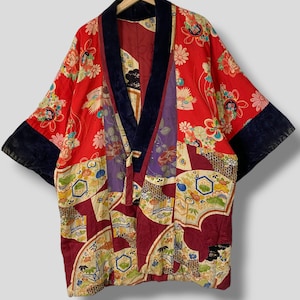 Könnte beinhalten: Ein rotes und burgunderfarbenes japanisches Kimono mit einem Blumenmuster und einem schwarzen Samtbesatz. Das Kimono ist aus Seide und hat ein traditionelles Design.