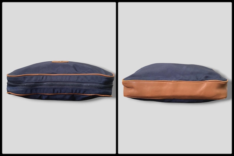 May include: Navy blue travel bag with a brown leather bottom and trim. The bag has a zipper closure and a small leather patch. The bag is shown from two different angles.
