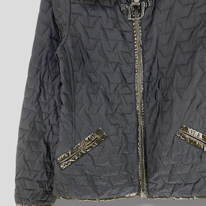 May include: A black quilted jacket with a zipper closure and a brown leather trim. The jacket has a stand-up collar and a diamond-shaped quilted pattern.