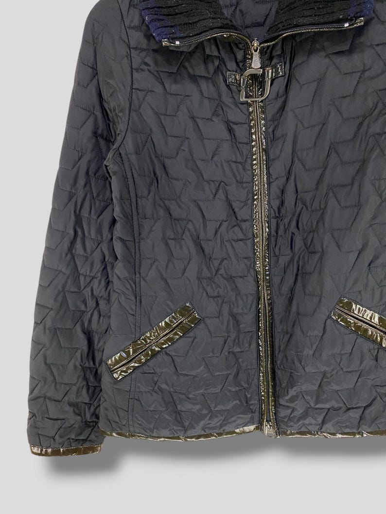 May include: A black quilted jacket with a zipper closure and a brown leather trim. The jacket has a stand-up collar and a diamond-shaped quilted pattern.